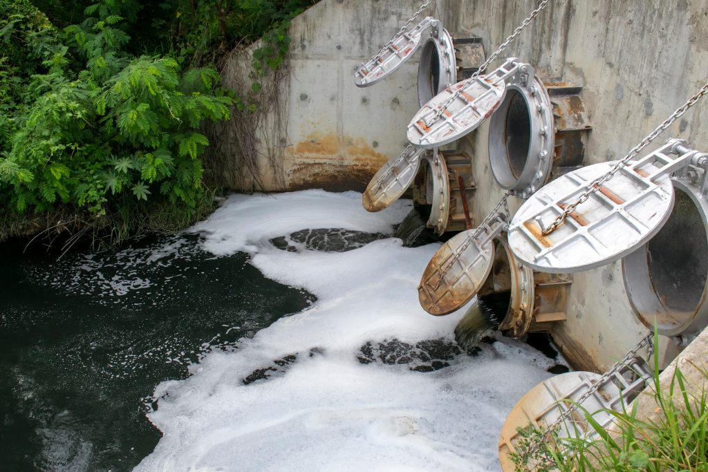 Waste water pipe from the factory flowing to the canal. Sewer pipes pouring out to the river polluting the environment from industrial factory.